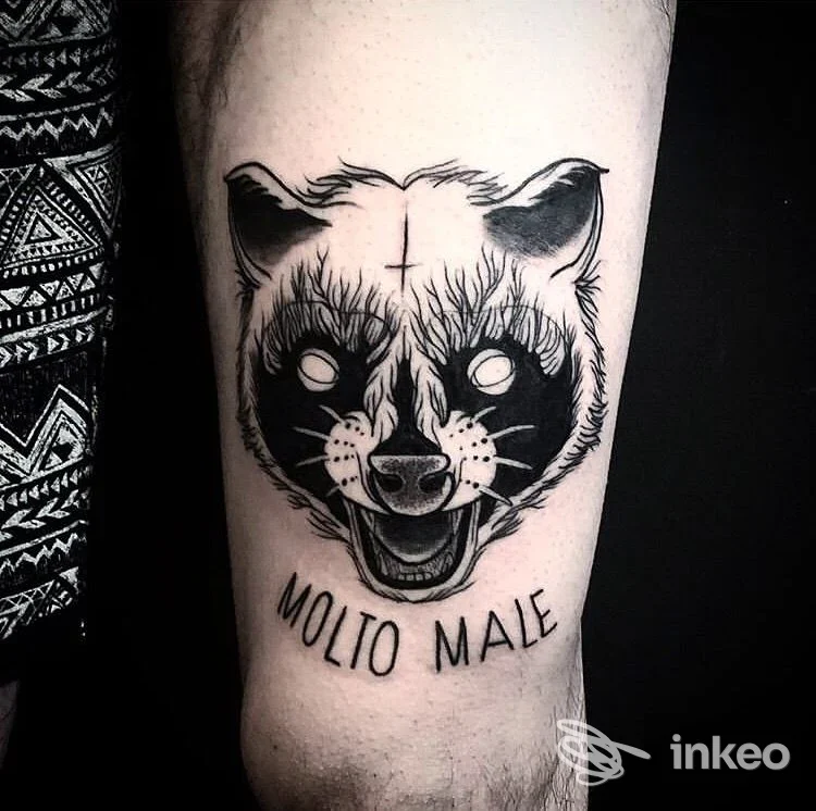 Tatuaggio su avambraccio raffigurante un volto di animale in stile linework in bianco e nero, testo Molio Male sotto l’immagine.