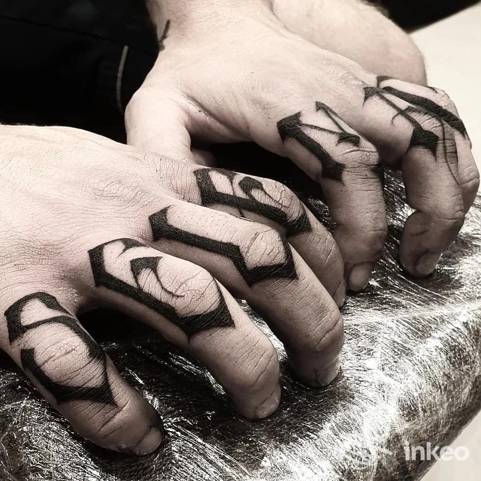 Due mani con tatuaggi geometrici neri sulle dita, poggiate su una superficie riflettente, scatto in bianco e nero. Studio Inkshiner Esthetic Lab.