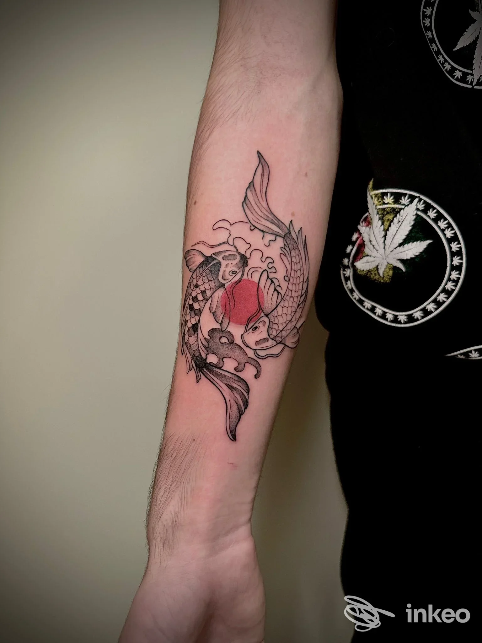 Avambraccio sinistro con tatuaggio a tema koi, in bianco e nero con accenti rossi, visibile in primo piano.