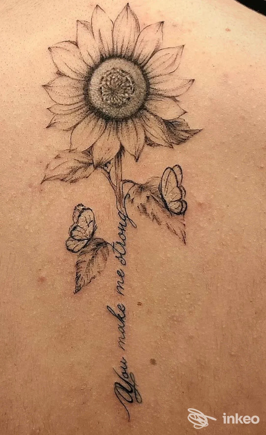 Tatuaggio realistico di un girasole con farfalle sulla pelle, eseguito sul dorso/schiena.