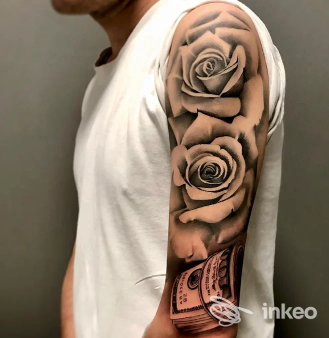 Tattoo a manica su braccio con rose in tonalità nere e grigie, visibile in primo piano, indumento bianco, senza interfacce social o testo.