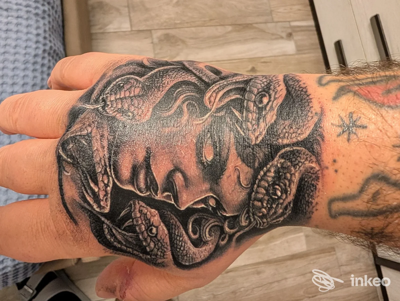 Dorso della mano e avambraccio con un tatuaggio in stile realistico, molto dettagliato, nero e grigio, senza visibilità del volto.