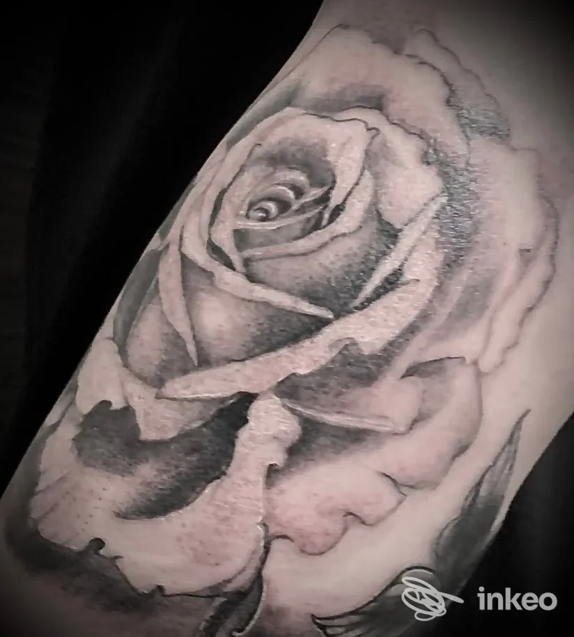 Dettaglio di un tatuaggio realistico su avambraccio sinistro: una rosa in tonalità di grigio e nero, con sfumature e contrasti ben definiti. Studio Zero 7 - Linea Tattoos Studio non riflesso o watermark visibile.