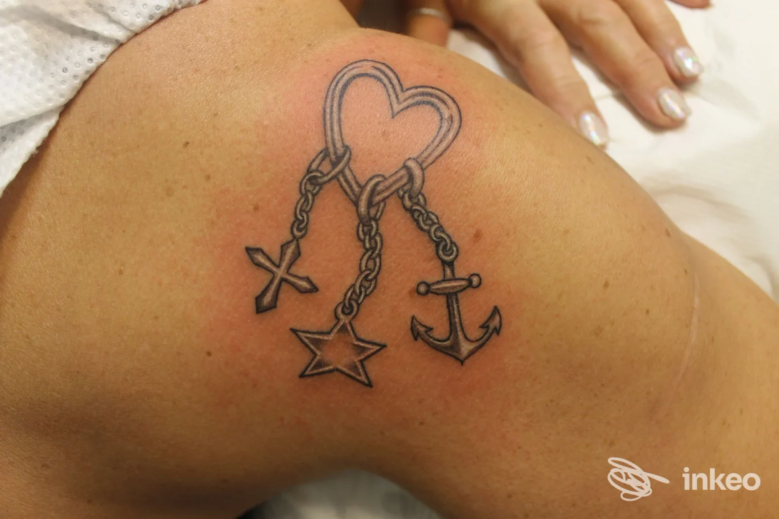Tattoo a cuore con catene, stella e ancora, disegnato sulla spalla di una persona, visibile in primo piano senza volto. Studio Il Tatuaggio, Italia.