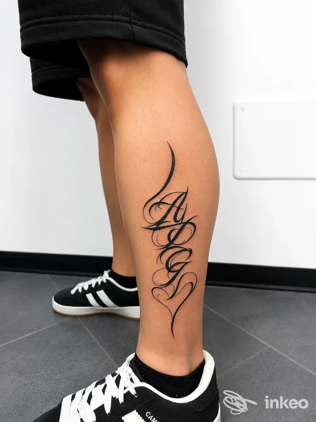 Tattoo calligrafico sul polpaccio di una persona, con scarpe sportive nere e bianche, visibile da vicino.