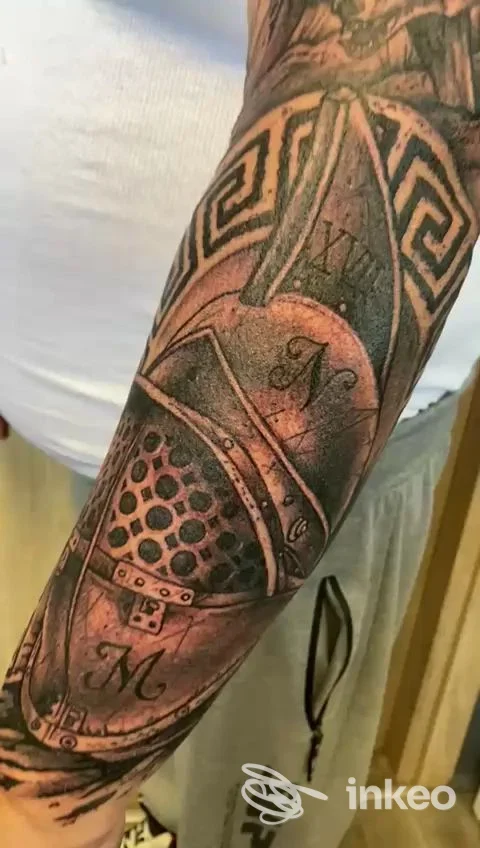 Braccio con tatuaggio complesso e stilizzato, linee scure e motivi geometrici, visibile su pelle, nessun volto presente.