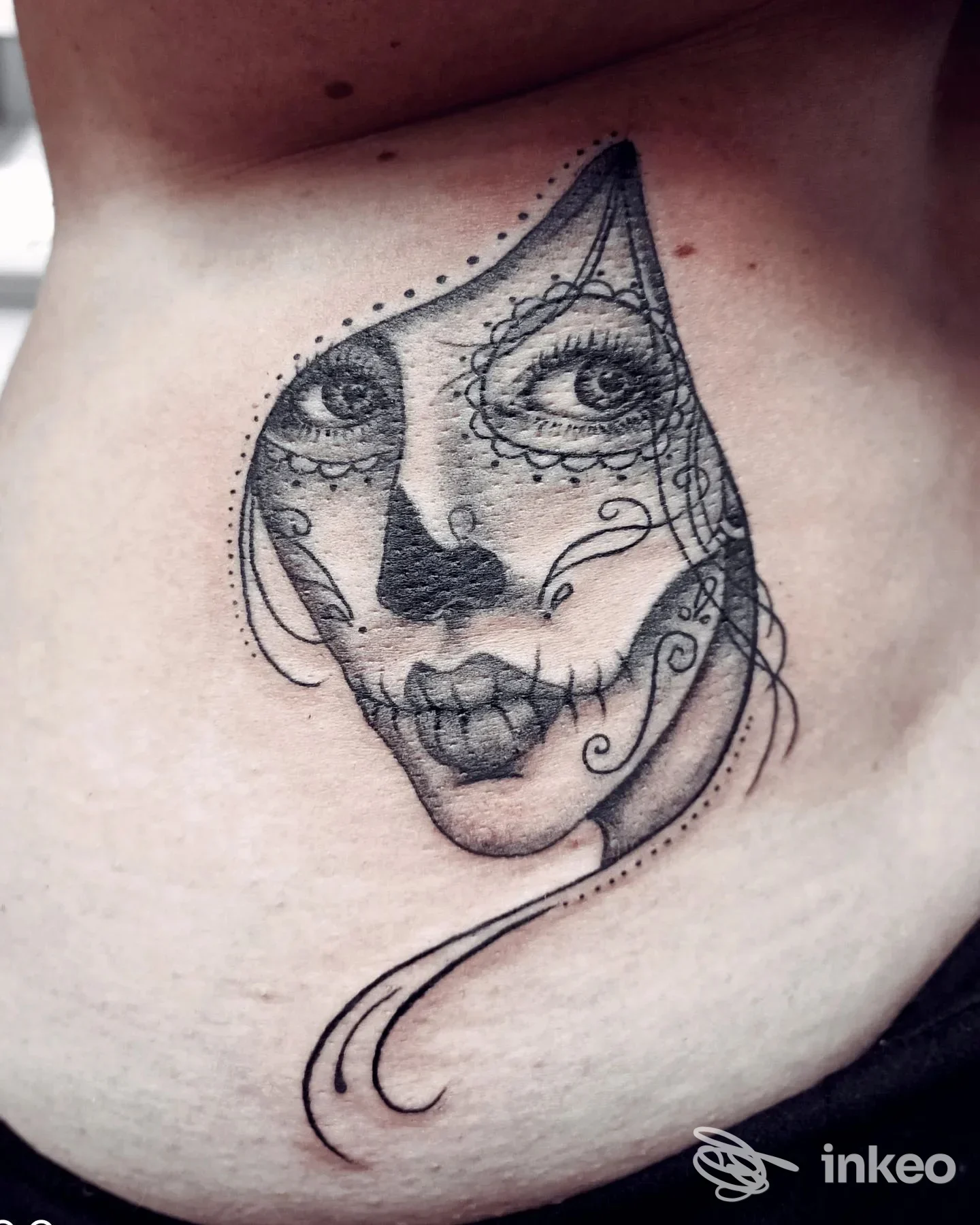 Tattoo sul fianco sinistro raffigurante una testa stilizzata in stile sugar skull con dettagli decorativi, realizzazione visibile sulla pelle.