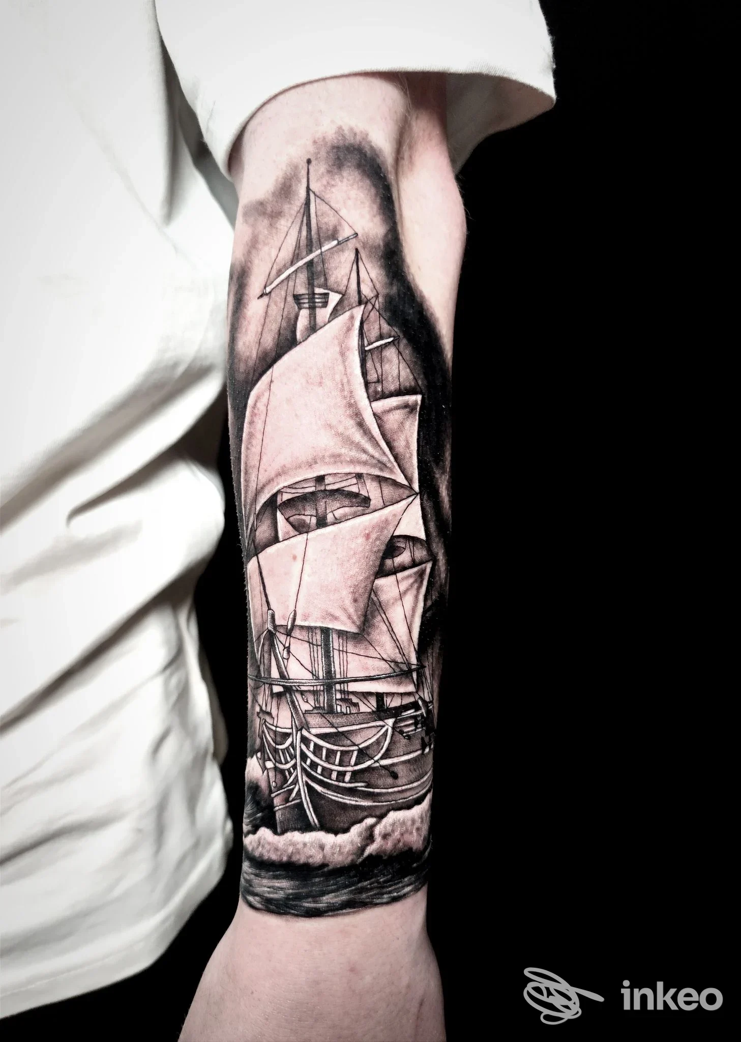 Tatuaggio realistico in bianco e nero di una nave a vela sull’avambraccio, con onde e dettagli delle vele, eseguito sulla pelle.