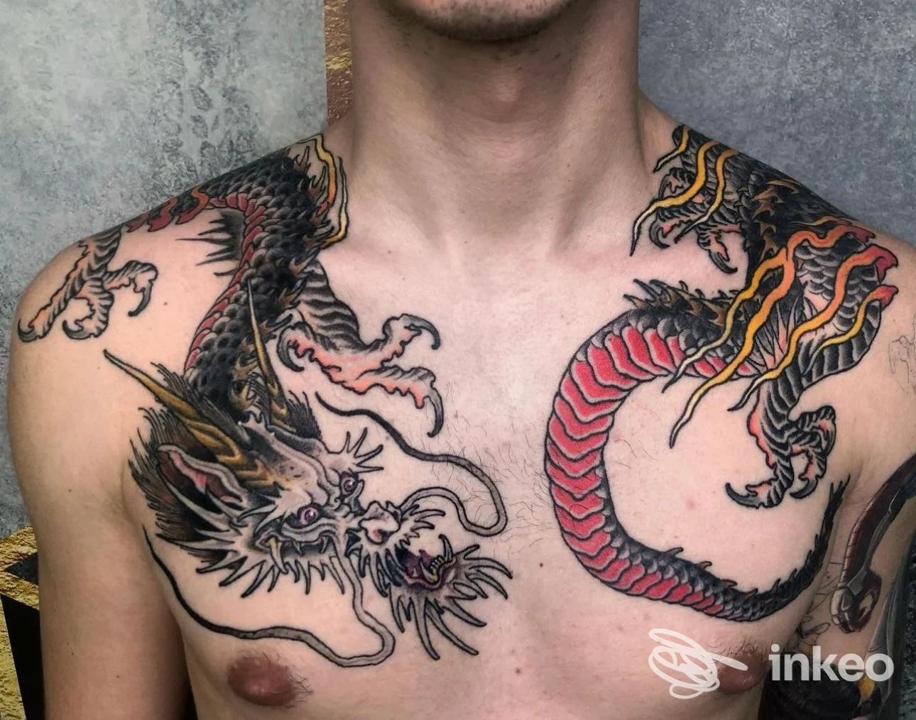 Tatuaggio sul torace di un drago, visibile su pelle reale di un uomo, con dettagli neri e rossi; nessun volto completo visibile né overlay sociale.