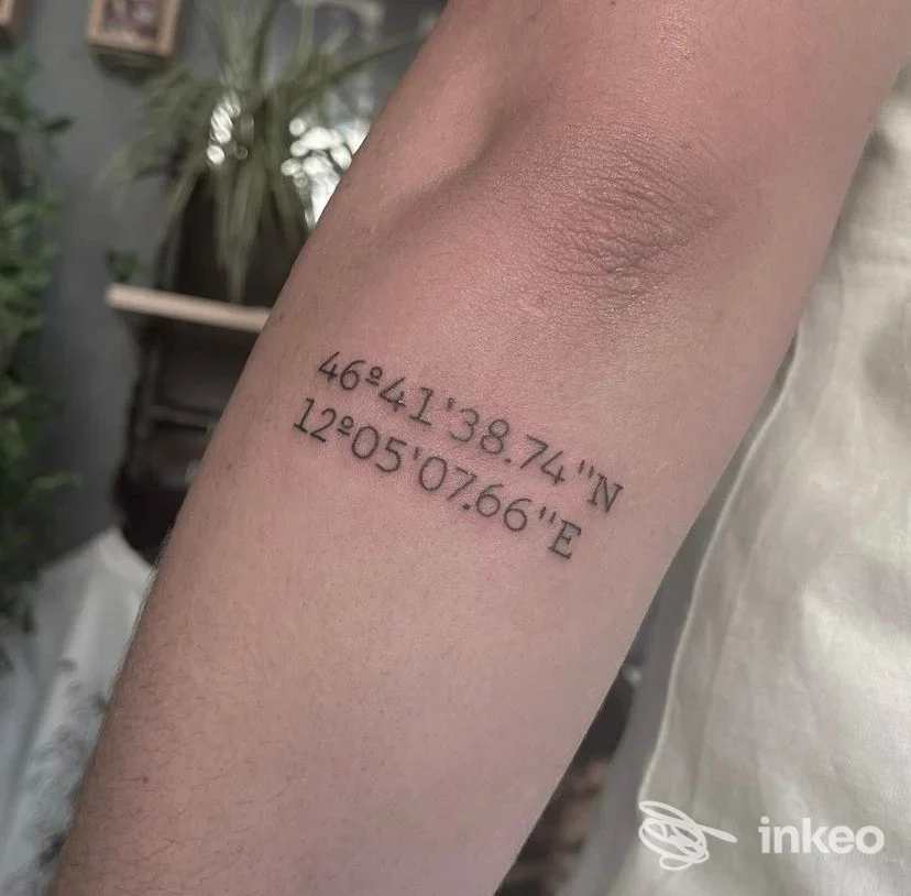 Tattoo sull'avambraccio con coordinate geografiche: 46°41'38.74"N 12°05'07.66"E, realizzato da MAS TINTA Studio.