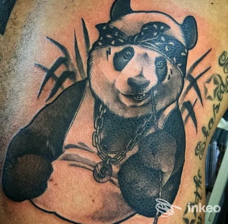 Tattoo visibile su pelle umana raffigurante un panda con bandana e catena, stile illustrativo su braccio.