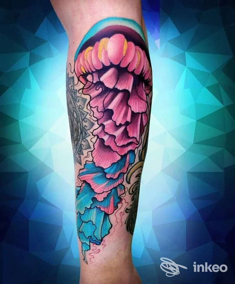 Tattoo colorato sull'avambraccio, raffigurante un motivo floreale con petali rosa e viola che sfumano in toni azzurri; ritratto su pelle reale, senza testo o elementi social.