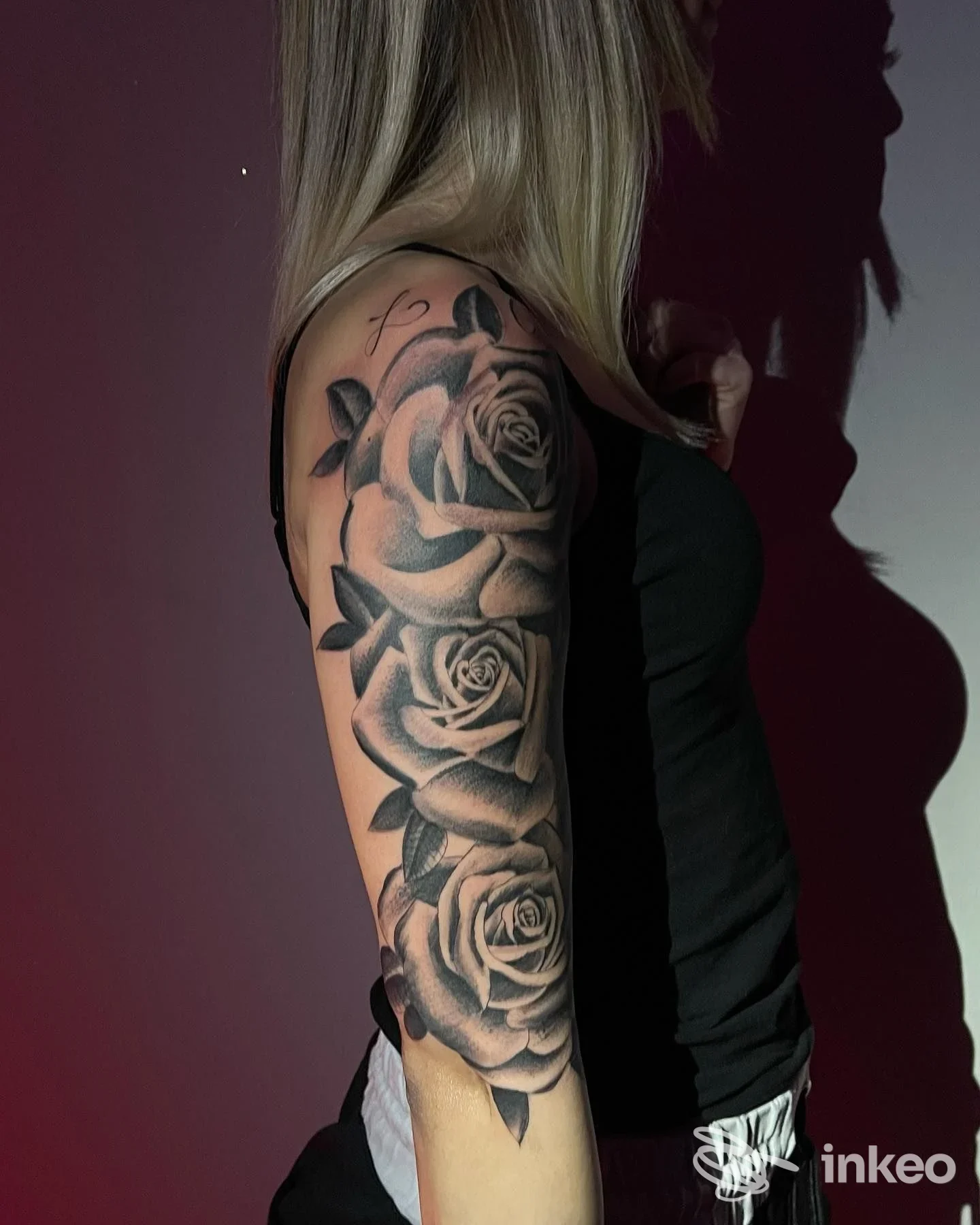 Braccio di una persona con tatuaggio a tema rose in bianco e nero, realizzato con tratteggio e gradazioni di grigio, visibile lateralmente.