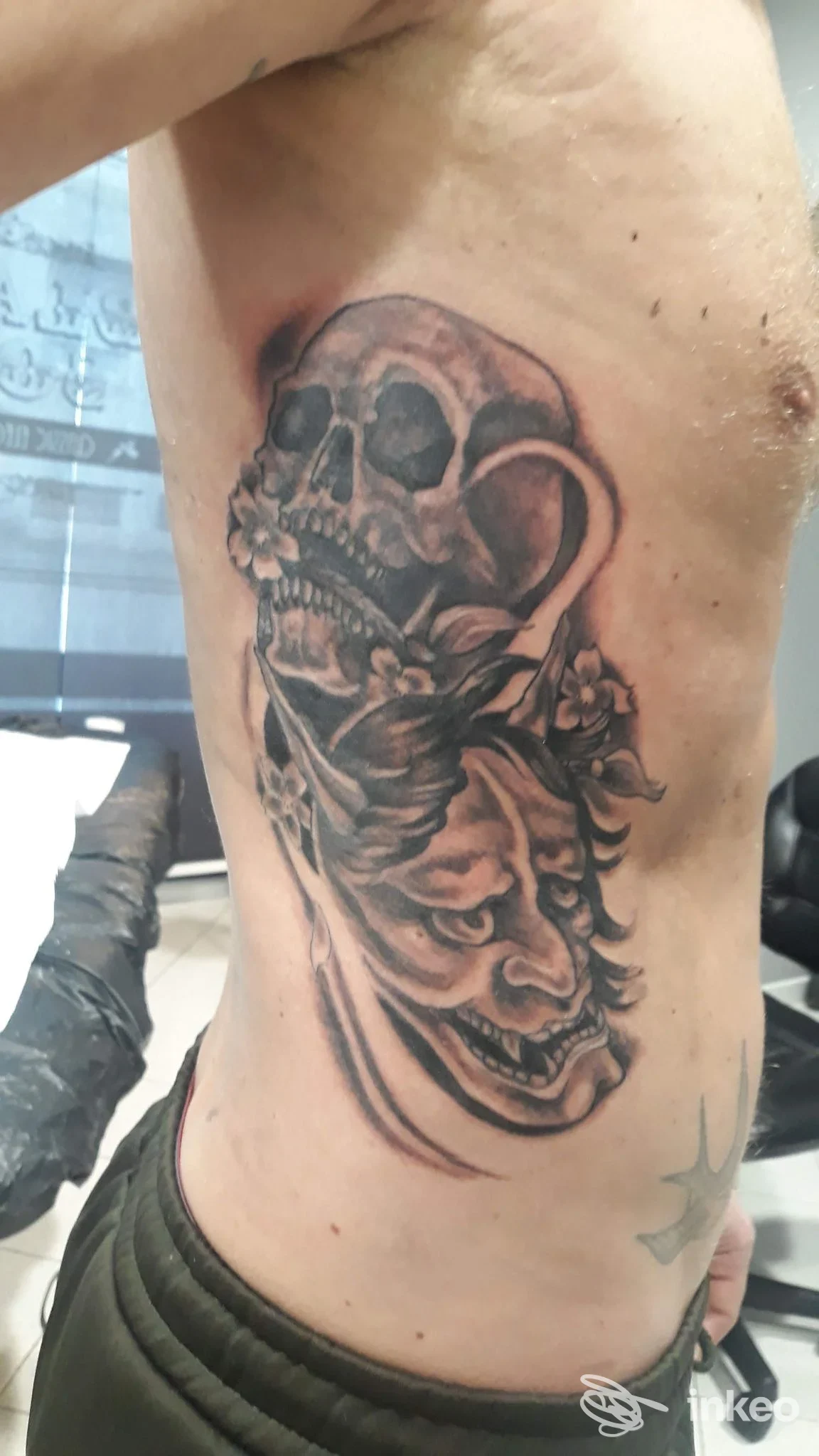 Tatuaggio sul fianco raffigurante un teschio e una figura decorativa, realizzato sulla pelle di una persona nello studio Black Soul Tattoo Parlour a Casalpusterlengo.