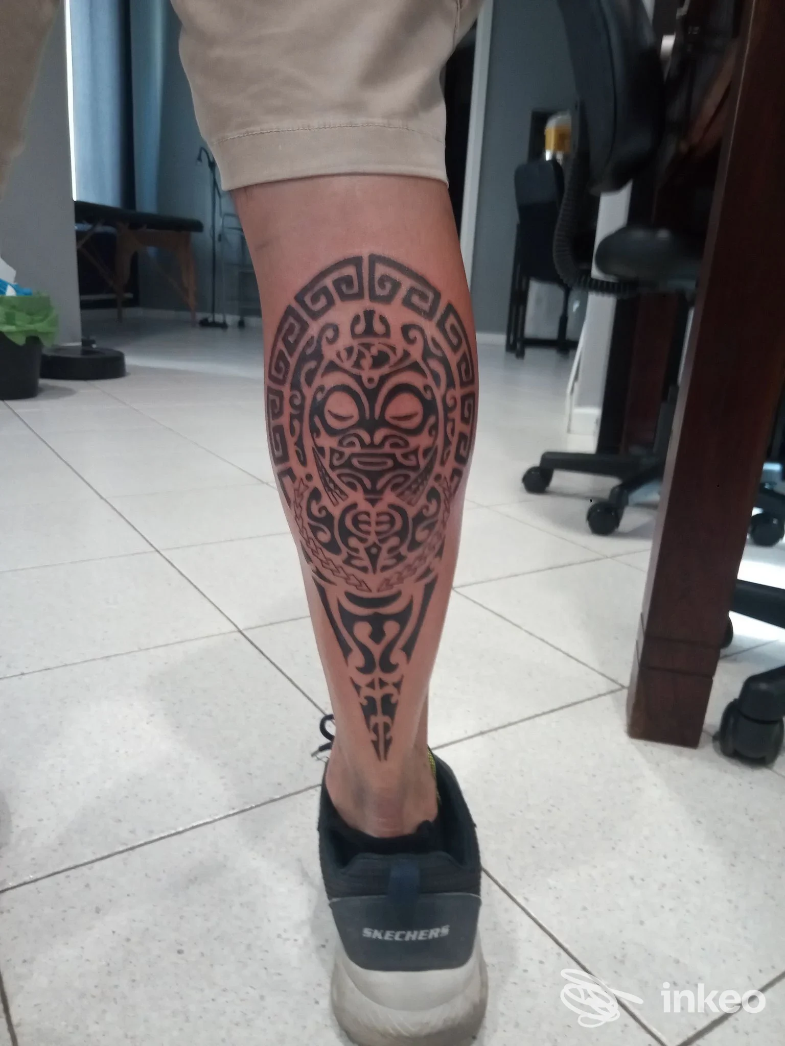 Tatuaggio ornamentale scuro e dettagliato su polpaccio di una persona, visibile senza volto.