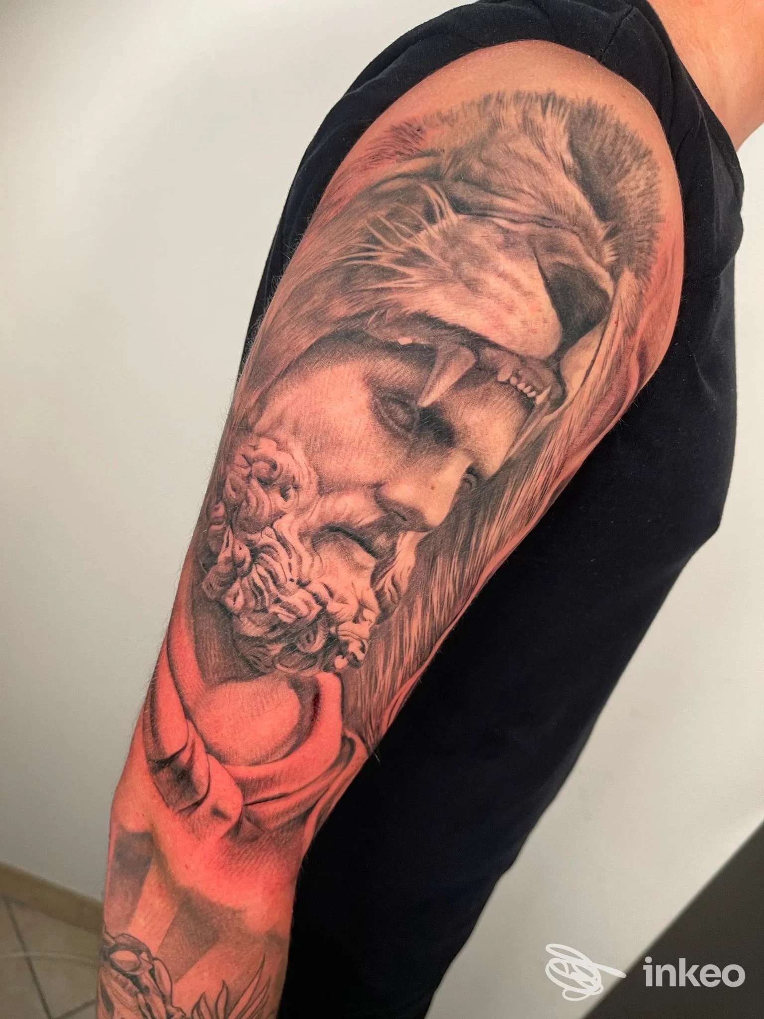 Tattoo realistico sul braccio: ritratto di una scultura antica in bianco e nero con riflessi rosati, realizzato da Shaki Tattoo.