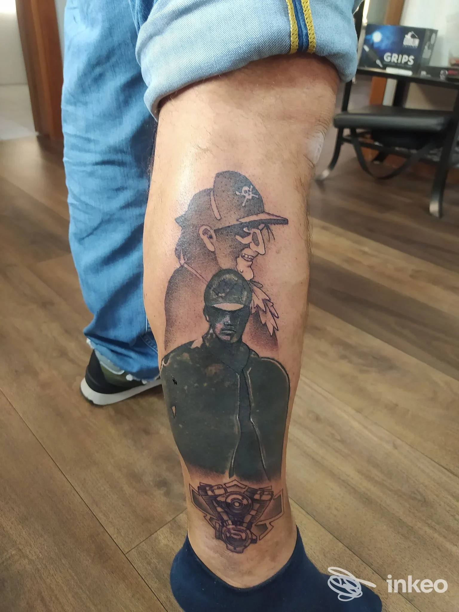 Tattoo su gamba destra raffigurante due figure: un uomo con cappello e un guerriero in uniforme, con dettagli aggiuntivi e grafica stilizzata nella parte più bassa.