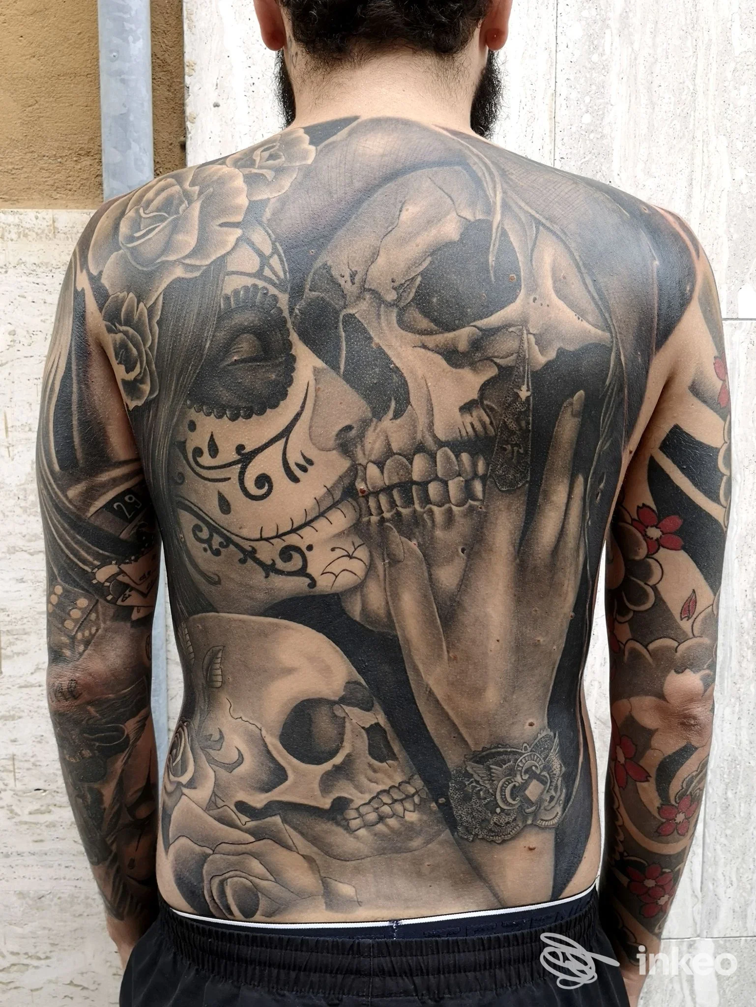 Schiena di un uomo vista di spalle con grande tatuaggio realistico che copre gran parte della superficie dorsale, nessun volto visibile.