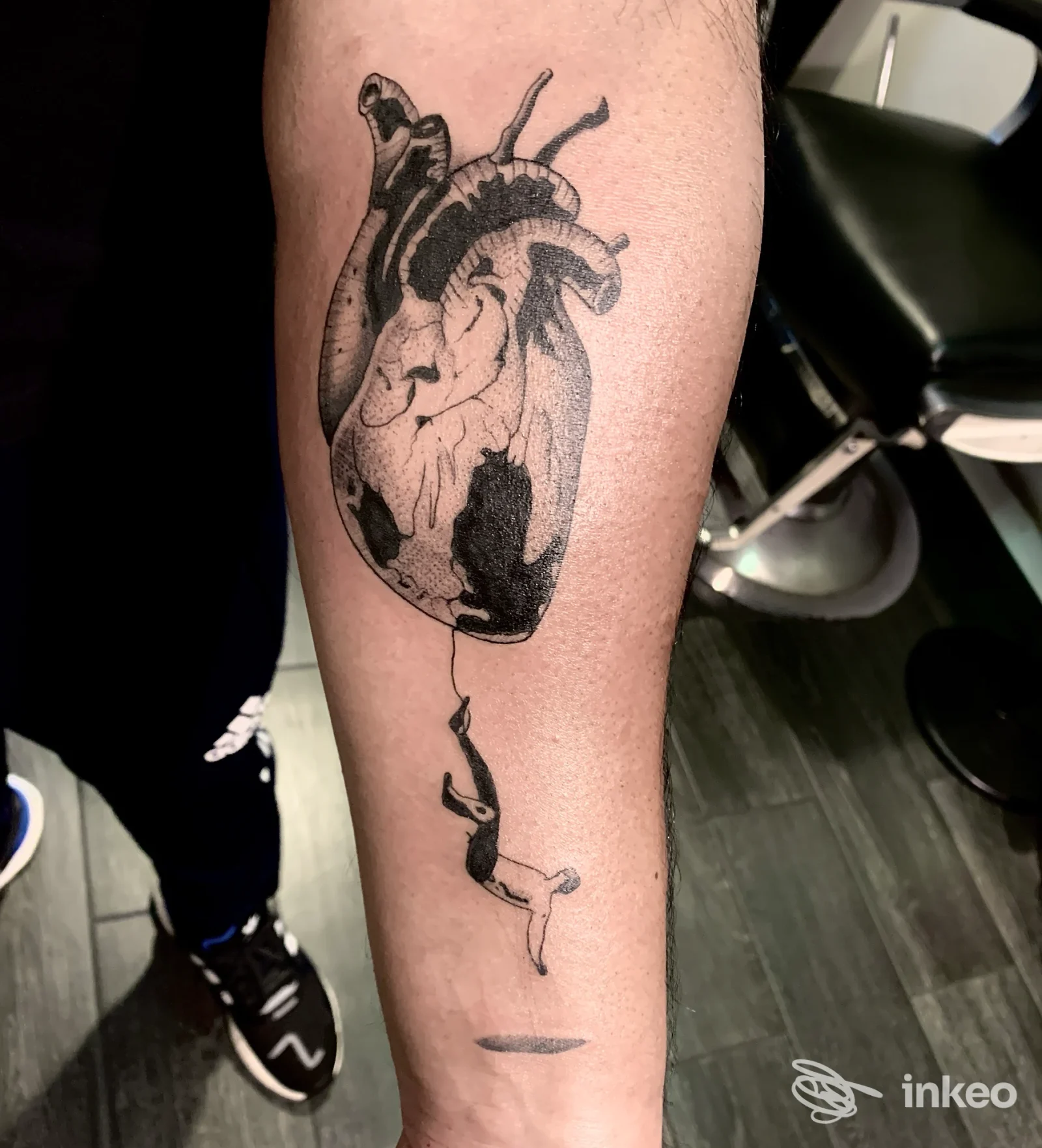 Tattoo realistico di cuore anatomico su avambraccio in bianco e nero, visibile in primo piano durante una sessione al Tattoo Parlour Since 1999.