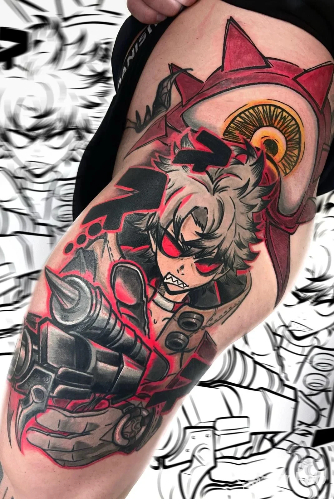 Tattoo valorizzato su braccio di un personaggio colorato con dettagli rossi e neri, visibile parte della coscia e pelle intorno; non è visibile volto completo.