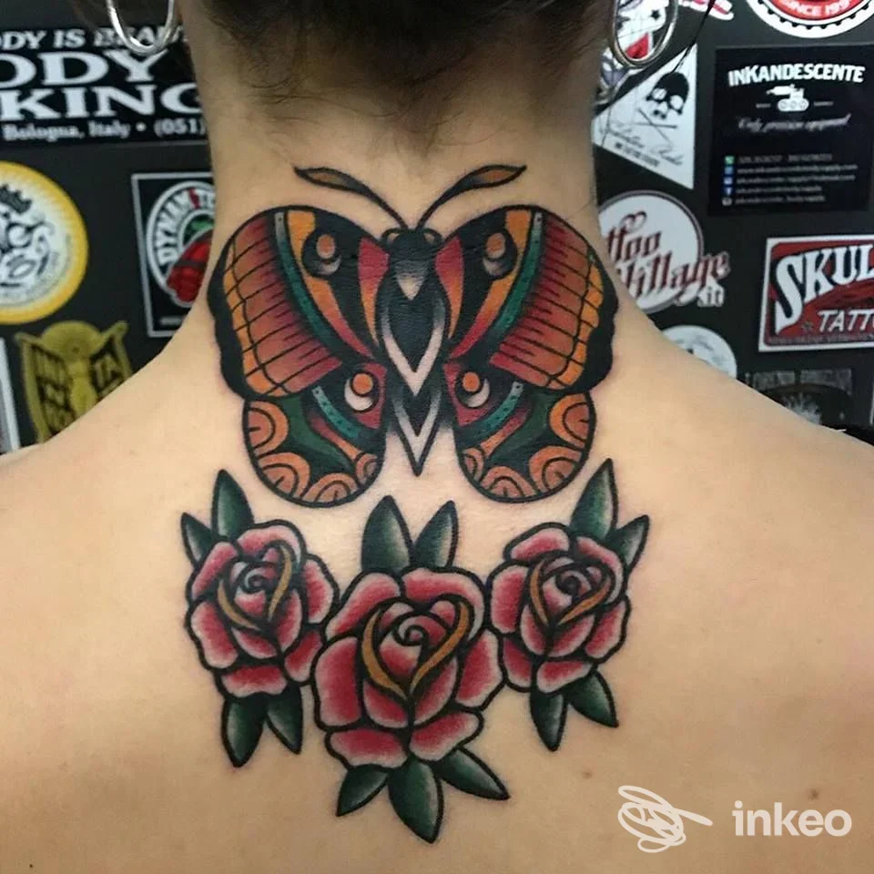Nuca e parte superiore della schiena di una persona con un tatuaggio colorato: una farfalla grande in alto e tre rose rosse con foglie verdi.