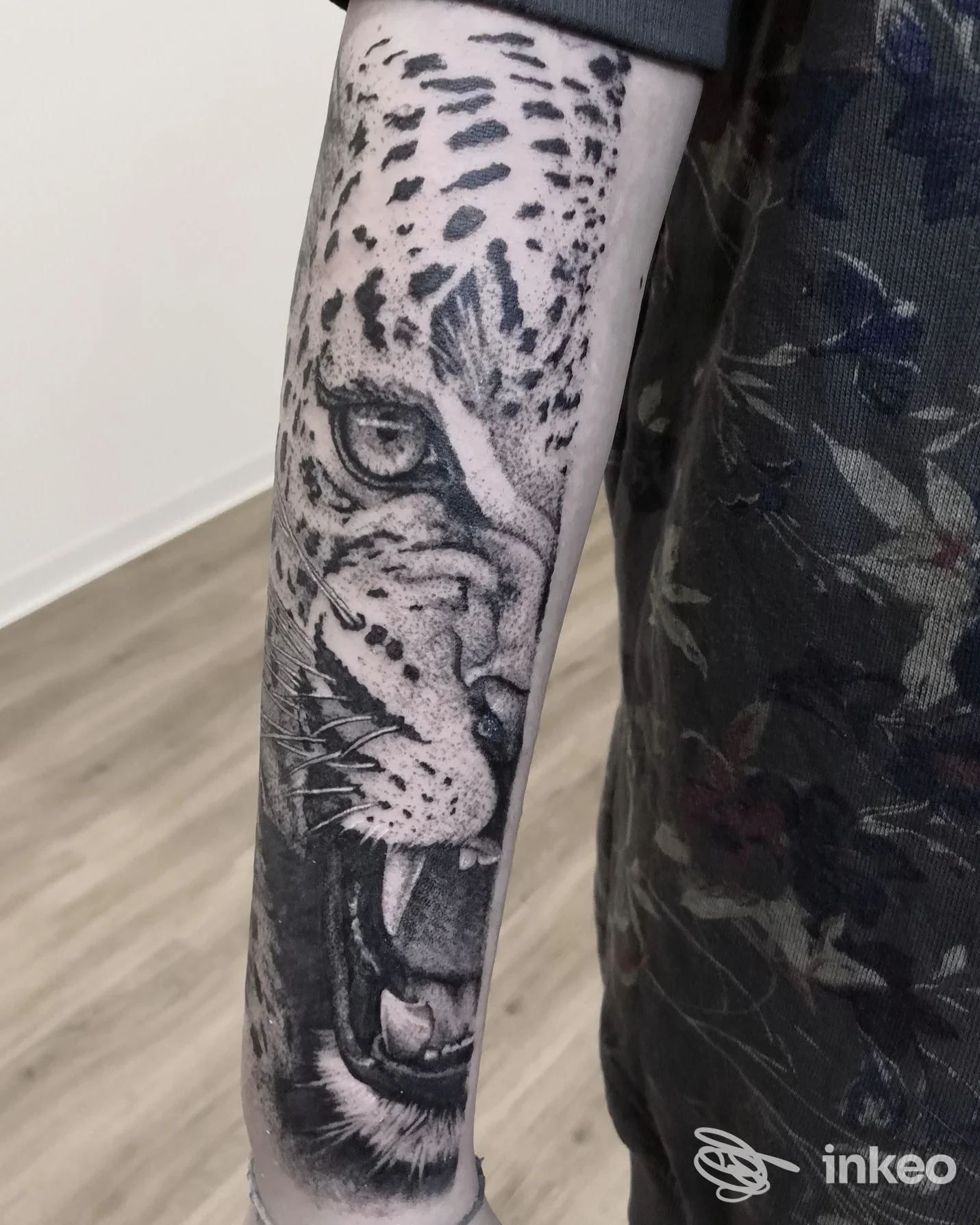 Tattoo realistico di una testa di leopardo sull’avambraccio sinistro, in tonalità nero/grigio, con dettagli di pelo e occhi, realizzato su pelle umana.