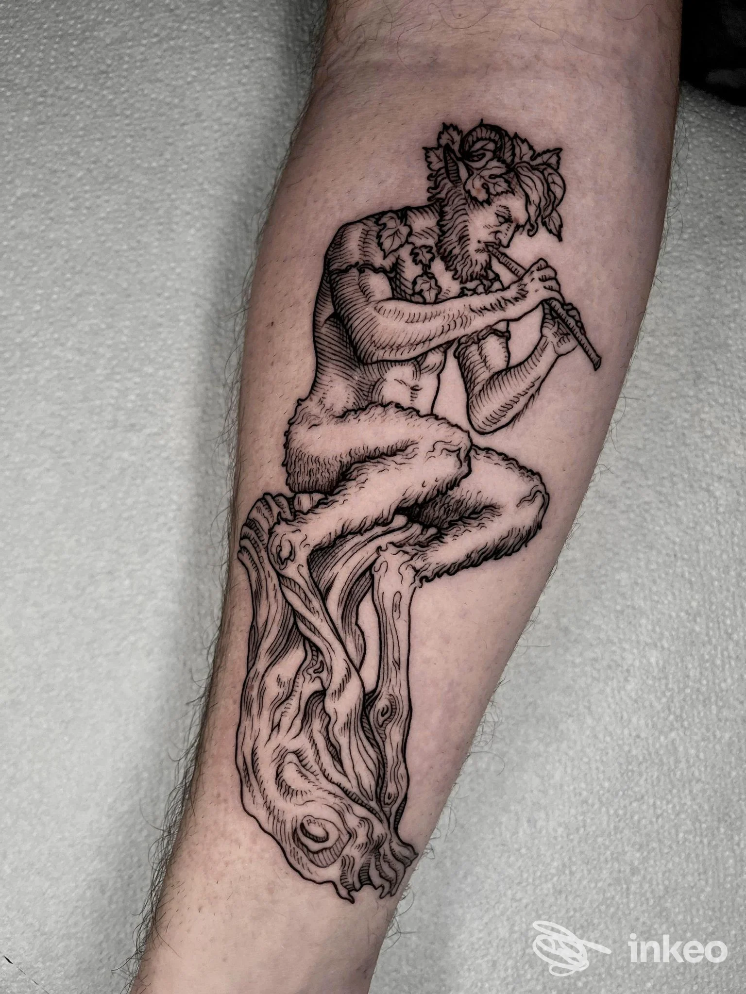 Un braccio con un tattoo in stile linework raffigurante una figura umana seduta, disegnata con linee scure, privo di elementi grafici estranei.