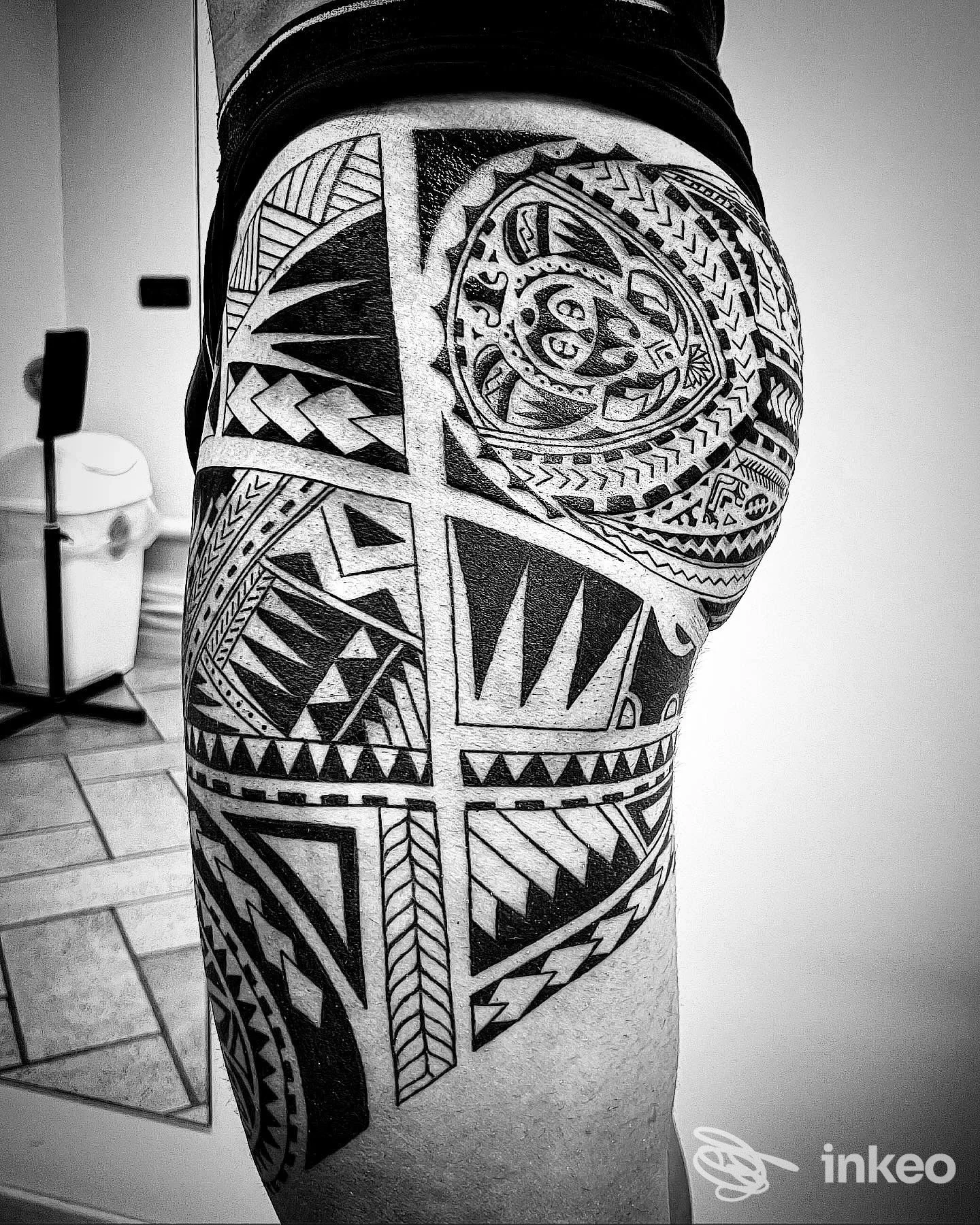 Tattoo geometrico in bianco e nero su coscia, motivi angulari e cerchi che occupano gran parte della pelle.