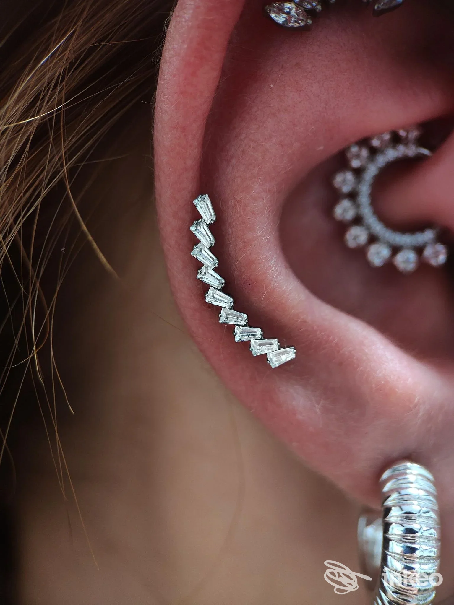 Piercing sull'orecchio visibile su padiglione auricolare, con gioielli metallici e decorazioni successive; non si vede alcun volto.