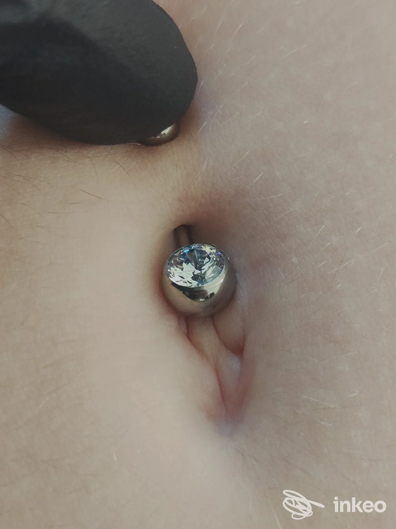 Piercing corporeo visibile su pelle umana con gioiello metallico tondo incastonato. non mostrano tatuaggi.