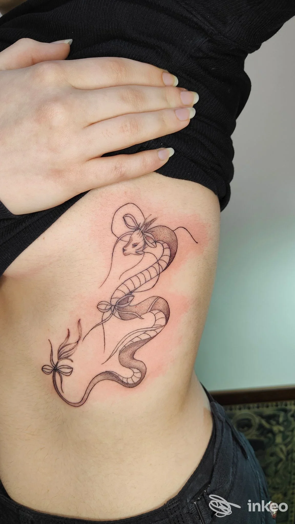 Tattoo su pelle visibile sul fianco sinistro di una persona, disegno stilizzato con linee sottili, nessuna interfaccia o testo visibile.