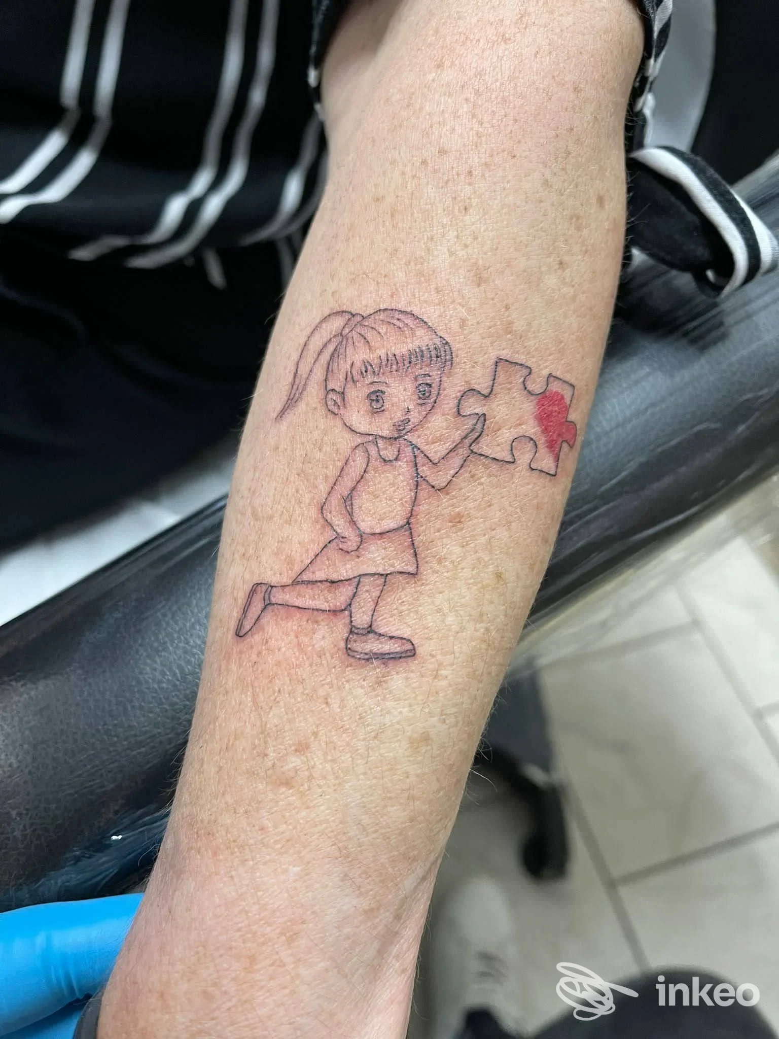 Tattoo su avambraccio raffigurante una bambina e un pezzo di puzzle, realizzato presso Quei Bravi Ragazzi Tattoo.