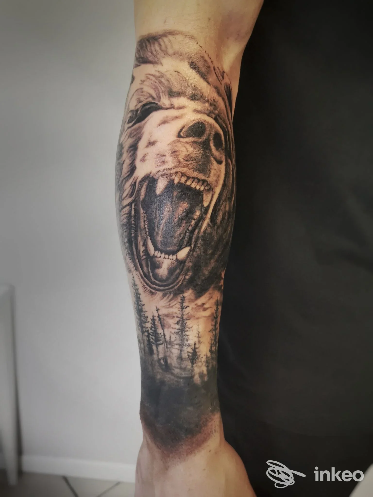 Tattoo realistico su avambraccio raffigurante una testa di orso urlante con paesaggio boschivo alla base, realizzato da Bleedink Tattoo a Brescia.