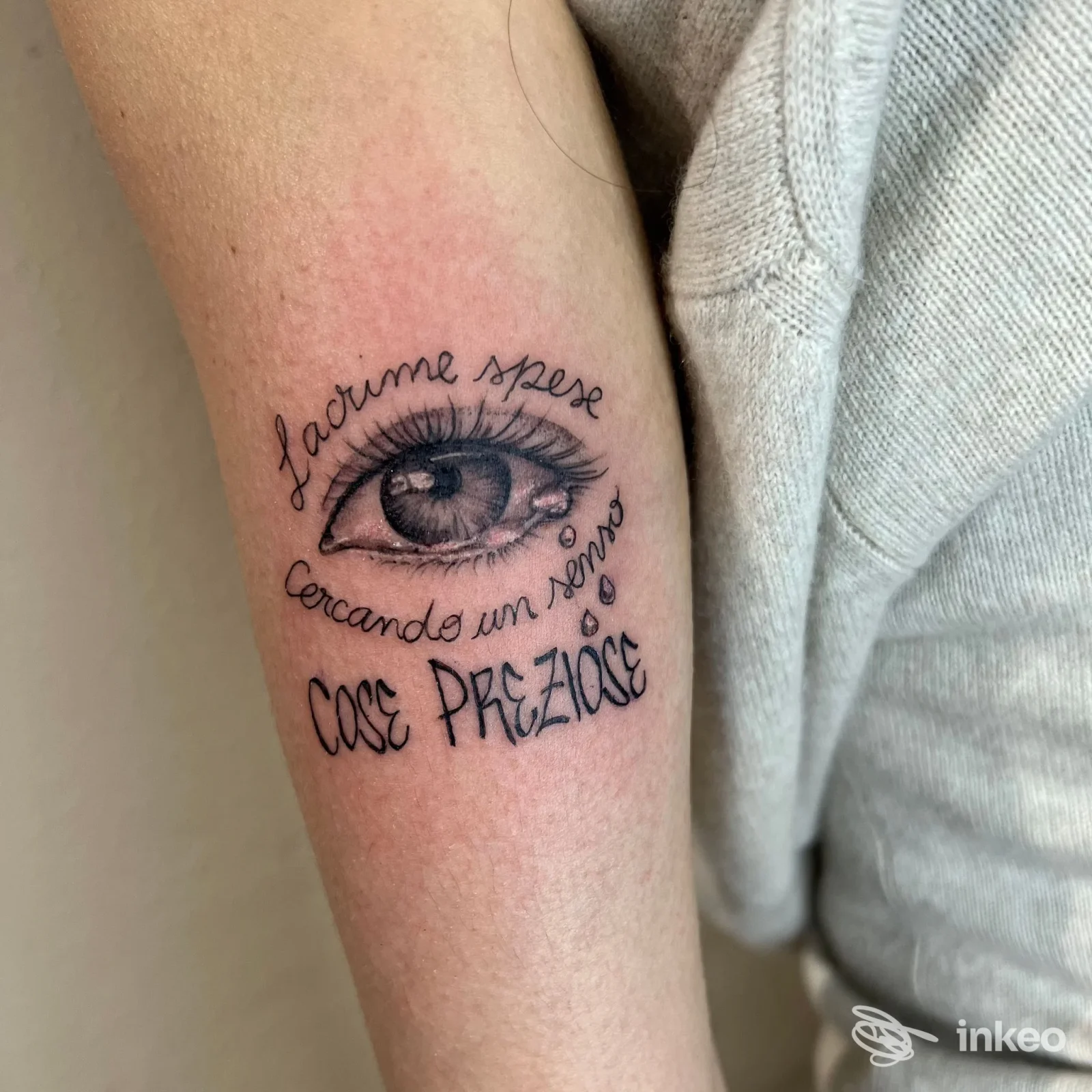 Tatuaggio sull'avambraccio raffigurante un occhio con testo circolare, realizzato da Feder Tattoo Studio a Lardirago, visibile su pelle chiara.
