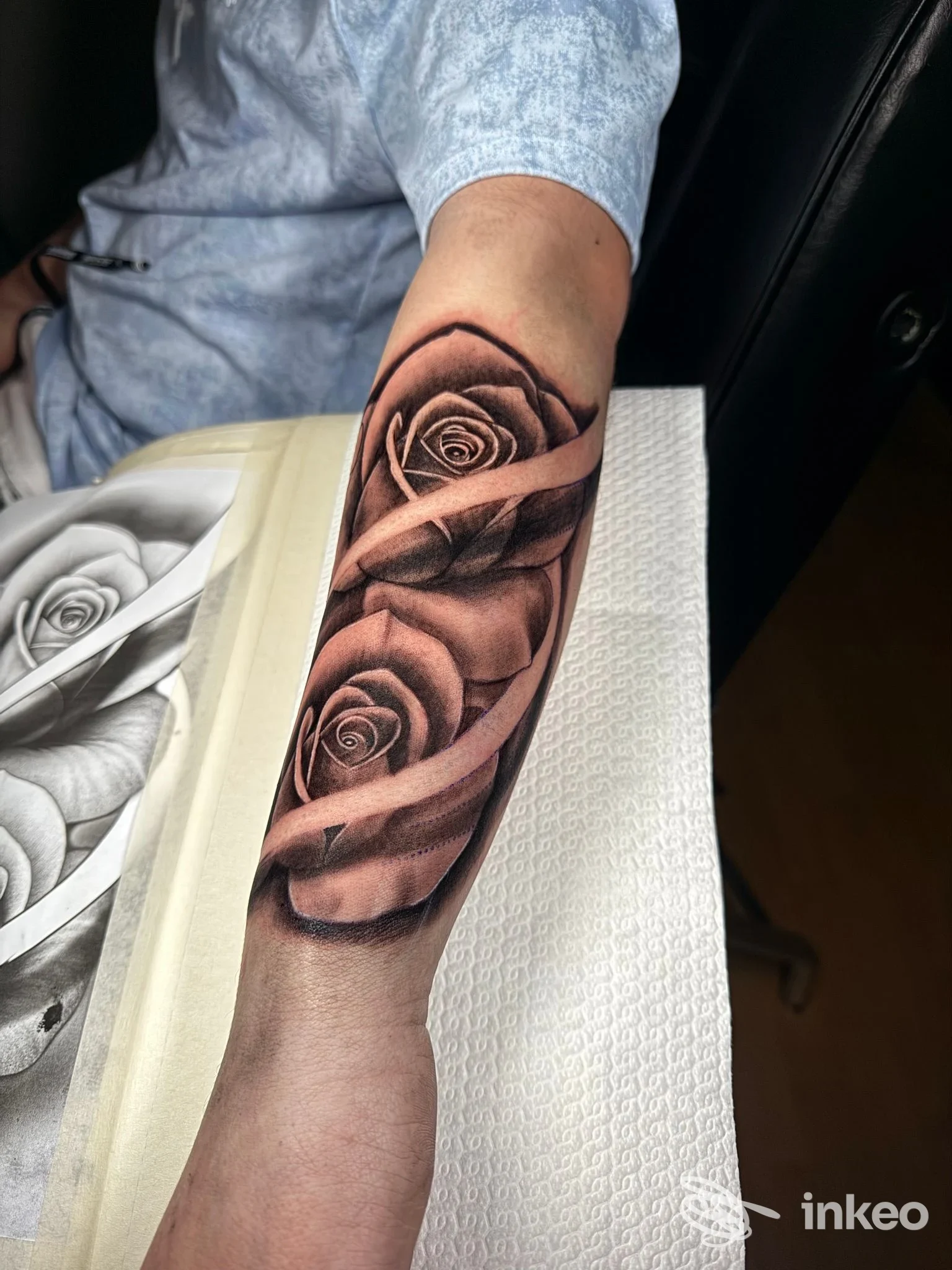 Tattoo realistico di rose su avambraccio, tonalità nere e grigie, dettagli precisi sui petali, realizzato direttamente sulla pelle.