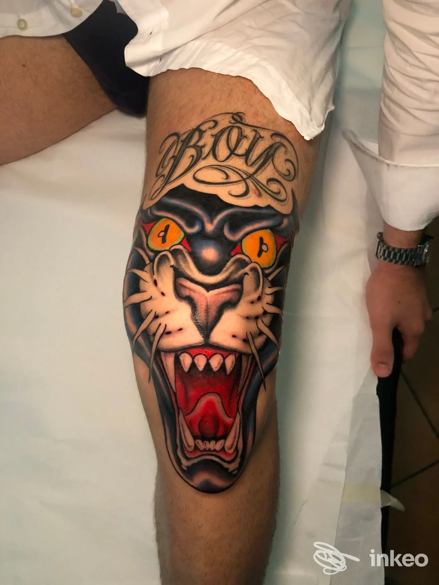 Tattoo realistico di una zampa di tigre con occhi arancioni sul polpaccio, colori vividi e contorni definiti, visibile su una gamba maschile, senza testi o elementi di interfaccia.