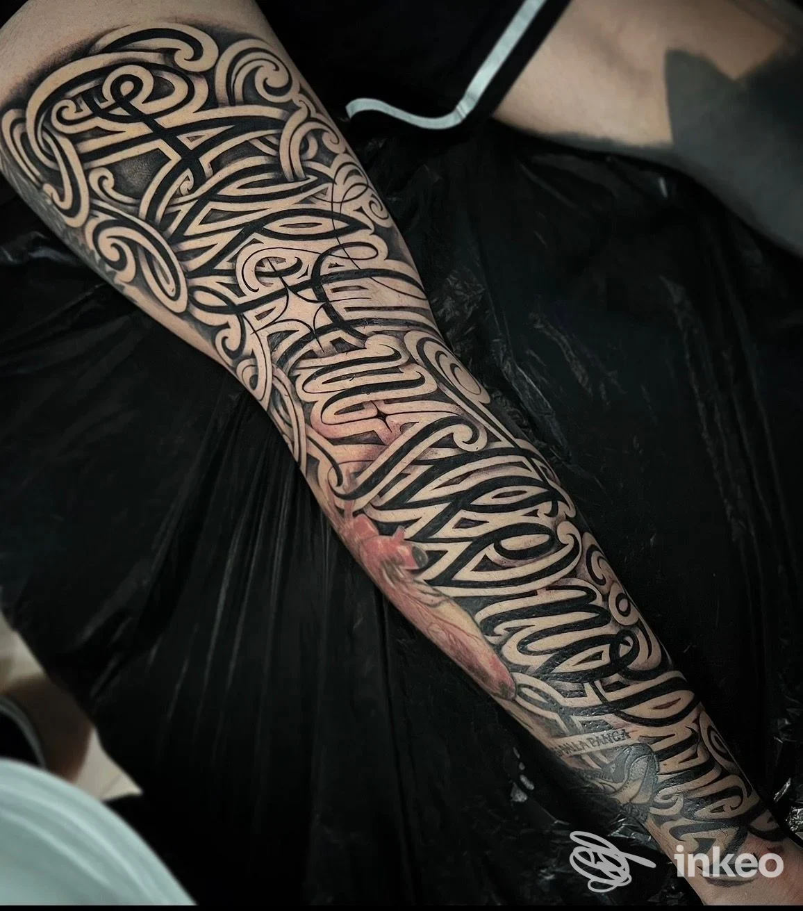 Tattoo sull'avambraccio con motivi intricati in bianco e nero, linee curve che si intrecciano lungo la pelle, senza volto visibile e senza testo o elementi di interfaccia.