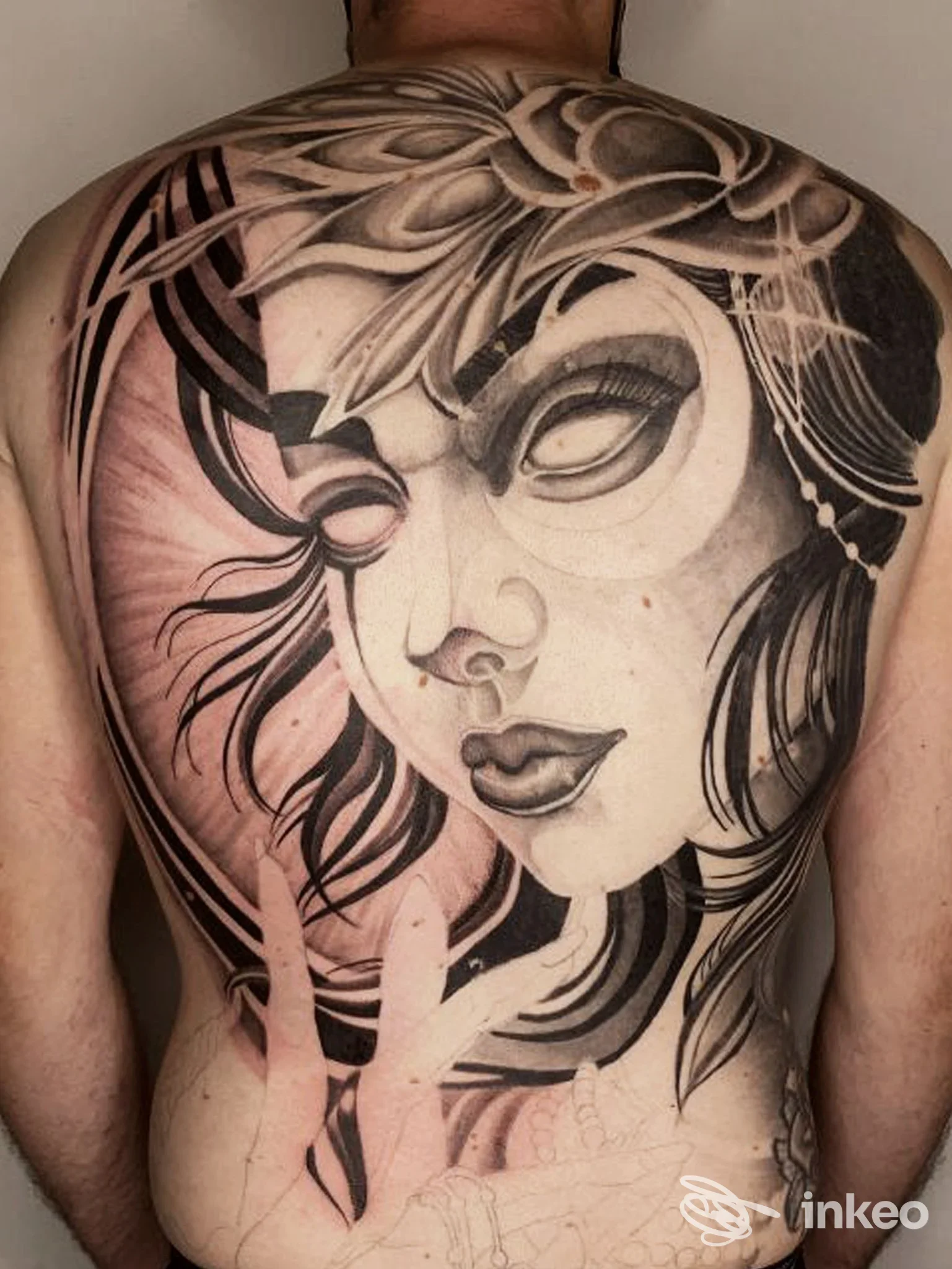 Tattoo su schiena raffigurante un volto femminile in stile grafico, disegno in bianco e nero con riflessi di luce e capelli fluenti. la scena mostra principalmente la schiena, senza altri elementi visivi prominenti, scatto singolo.