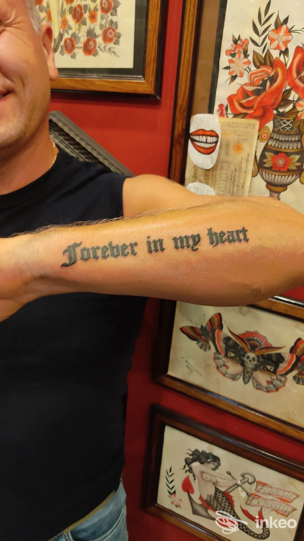 Braccio visibile con tatuaggio di testo in stile gotico, forese