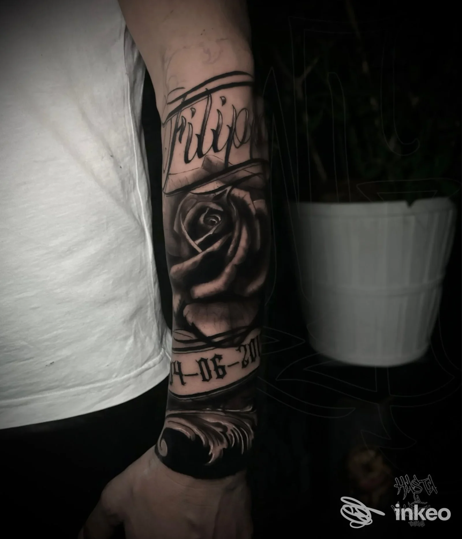 Primo piano di braccio con tatuaggio realistico a rosa e testo nero, eseguito su pelle, scatto in studio. Studio Hasta La Muerte Tatuajes.