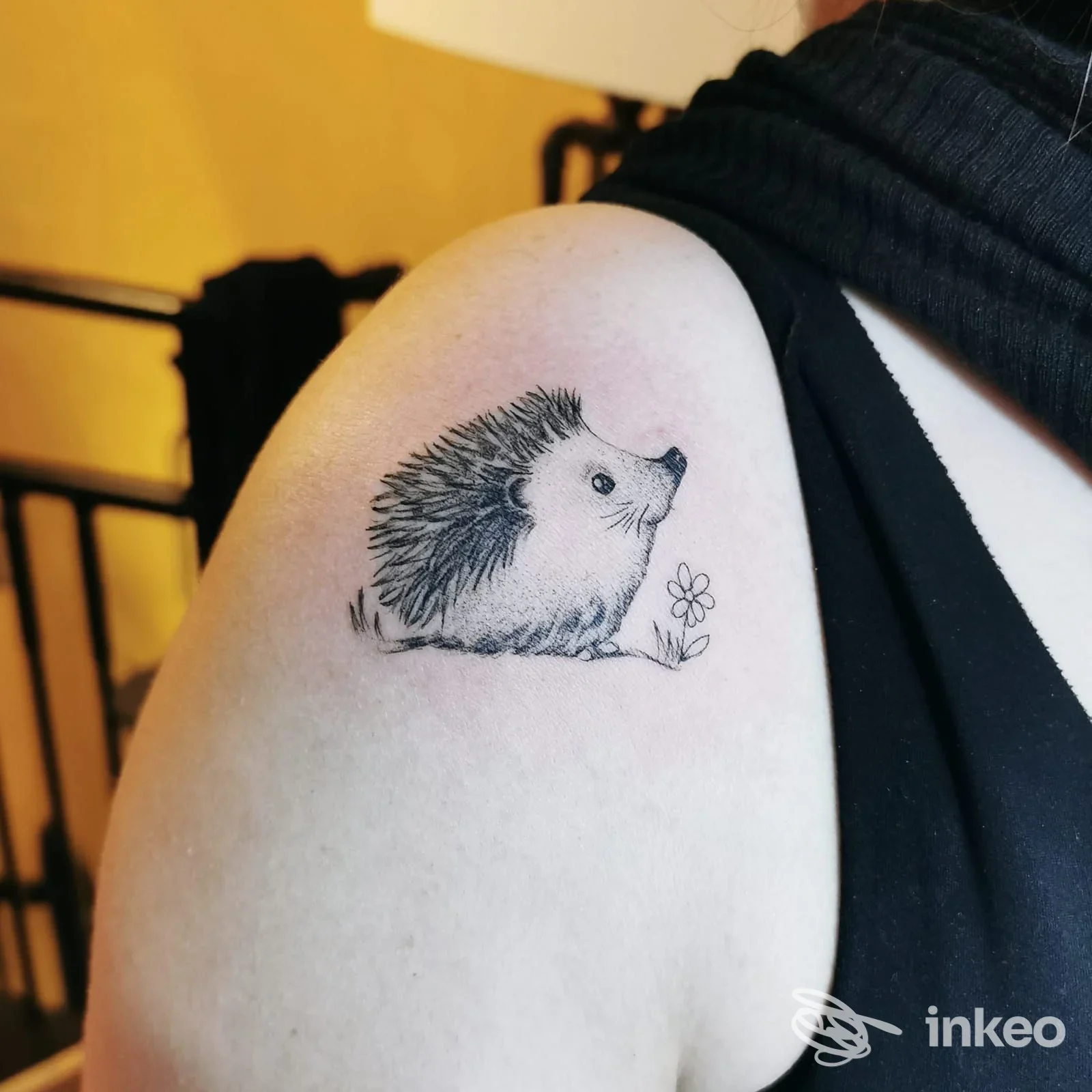 Tattoo raffigurante un riccio con fiore sul braccio, realizzato sulla pelle, senza testo né watermark visibile.