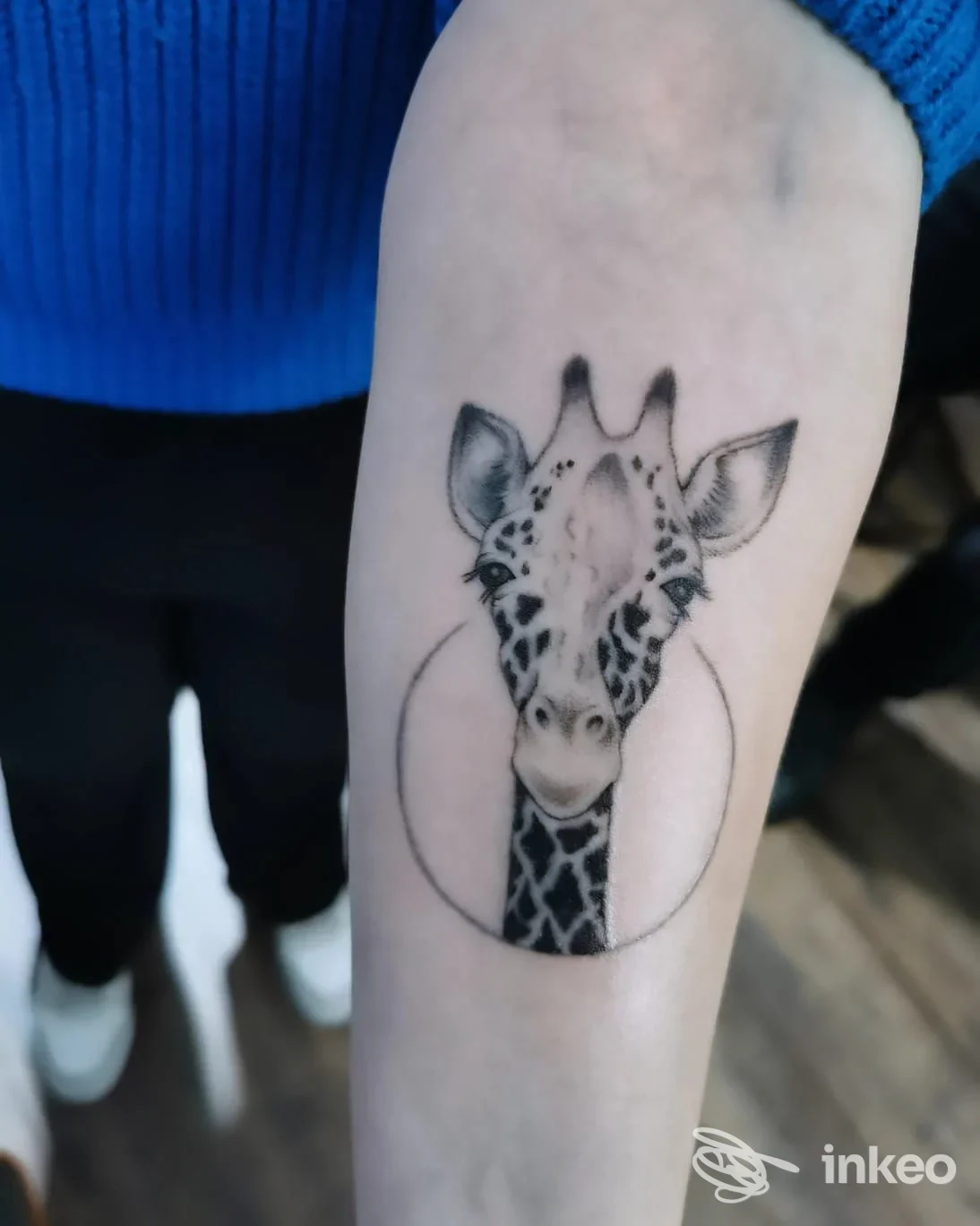 Tatuaggio su pelle raffigurante una giraffa all'interno di un cerchio, eseguito sul braccio.
