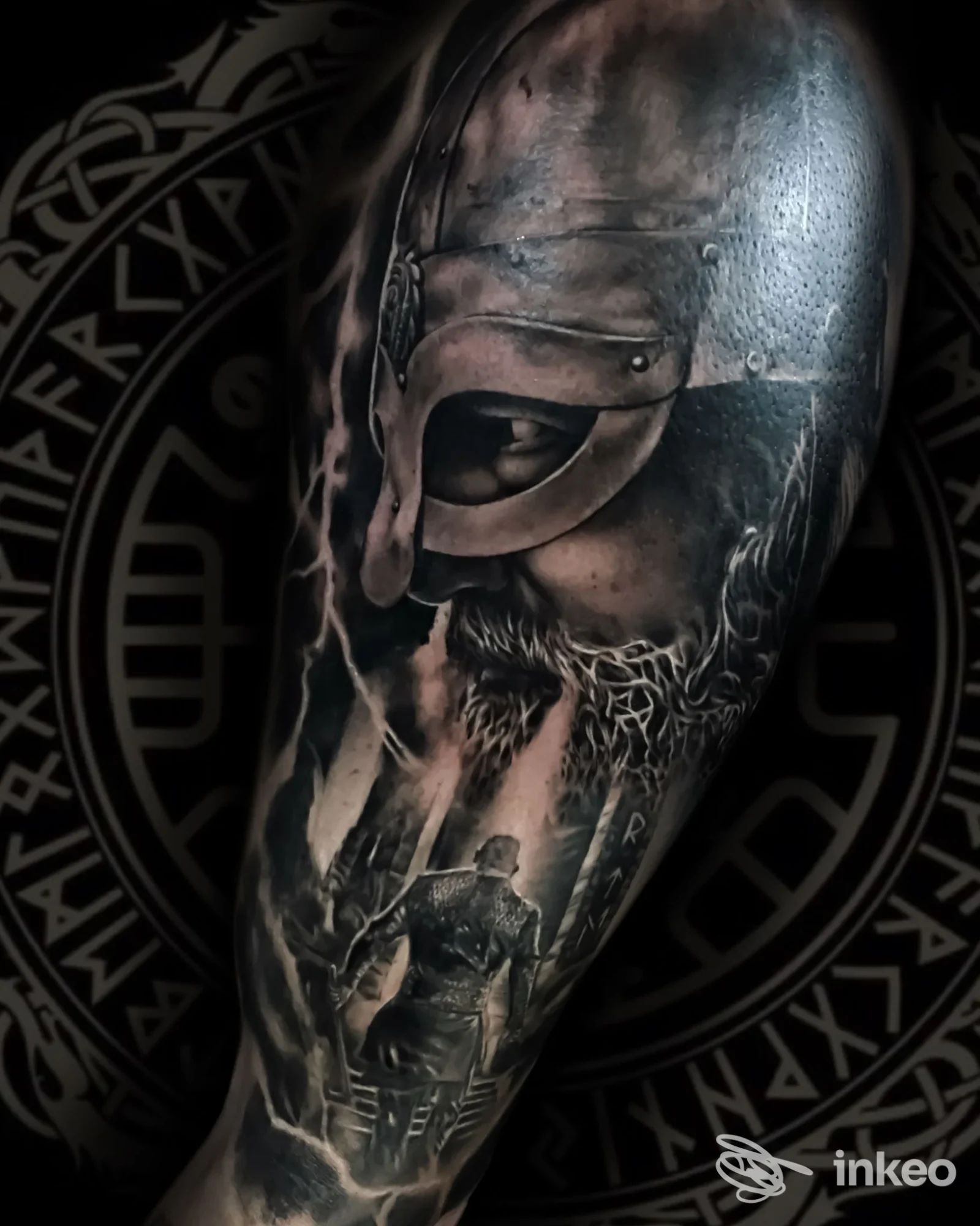 Tattoo realistico su avambraccio raffigurante figura guerriera medievale, con dettagli d’ombra e texture metalliche su sfondo scuro; non si vede volto, studio Artemista Tattoo e città non specificata.