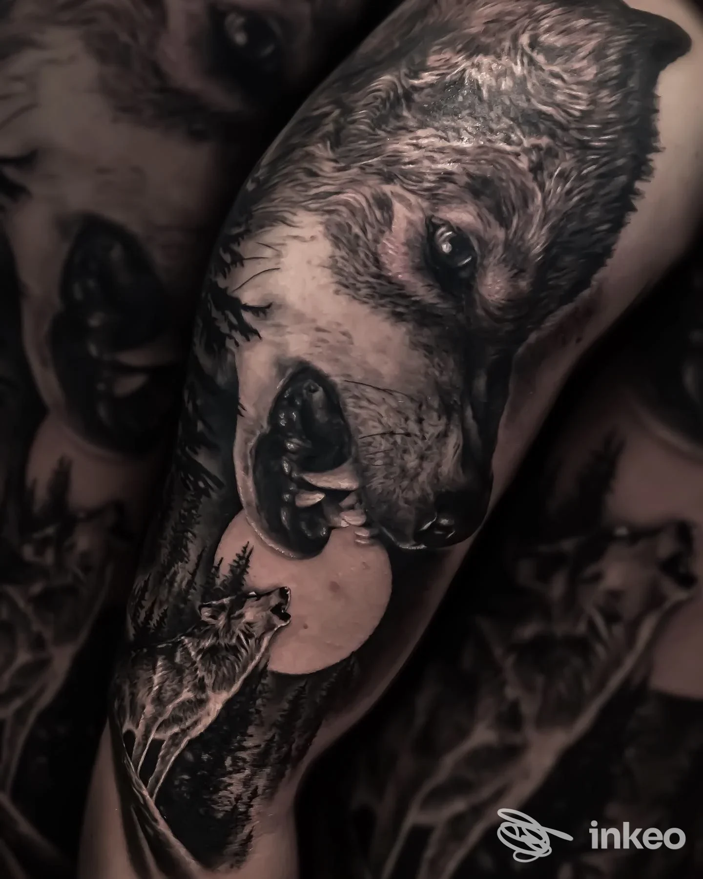 Tattoo realistico di orso sul braccio, con foresta e luna, in tonalità scure.