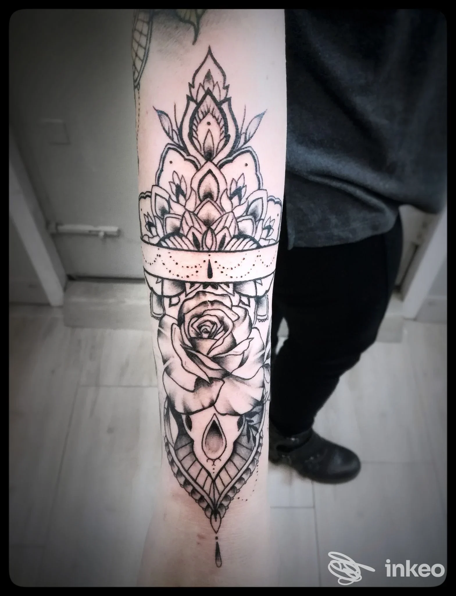 Tatuaggio visibile sull'avambraccio sinistro: disegno in bianco e nero con motivo mandala e rosa centrale, realizzato direttamente sulla pelle in una foto dall'avambraccio inferiore.