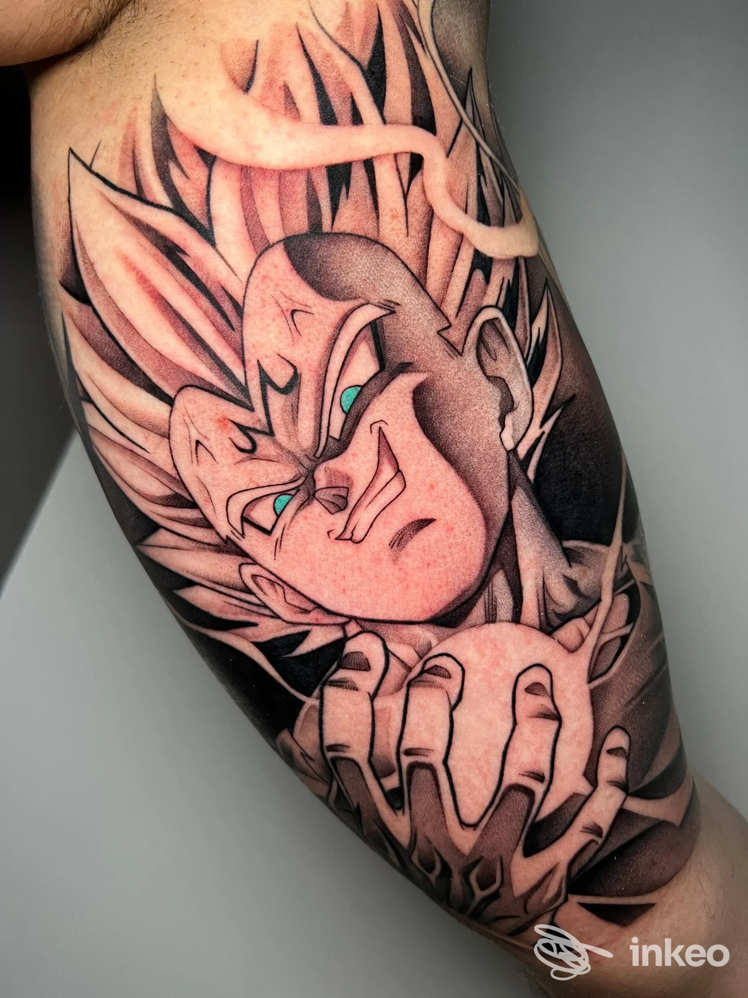 Tattoo a braccio raffigurante un personaggio in stile anime Dragon Ball con linee nere marcate, sfumature rosa e particolari di colore azzurro sull’occhio, braccio tatuato ben visibile.