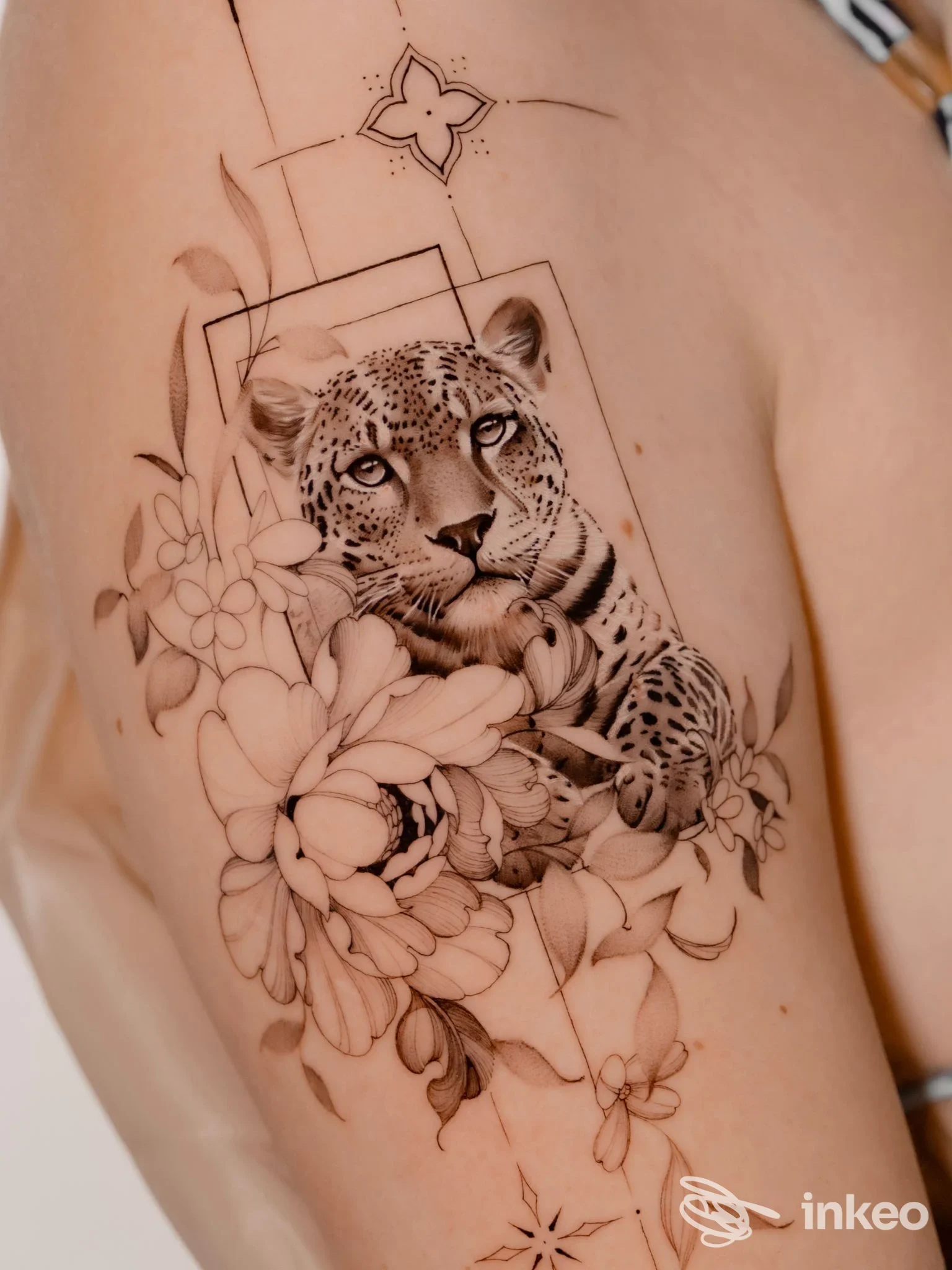 Tattoo realistico su pelle: leopardo circondato da fiori, realizzato sul braccio. Visuale chiara della realizzazione corporea senza overlay o testo promozionale.