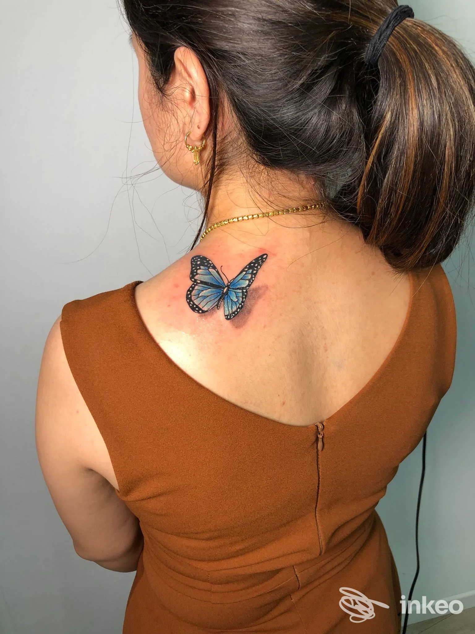 Tatuaggio reale di una farfalla blu sulla nuca di una donna, scatto singolo nello studio Sacrifice Tattoo Studio.