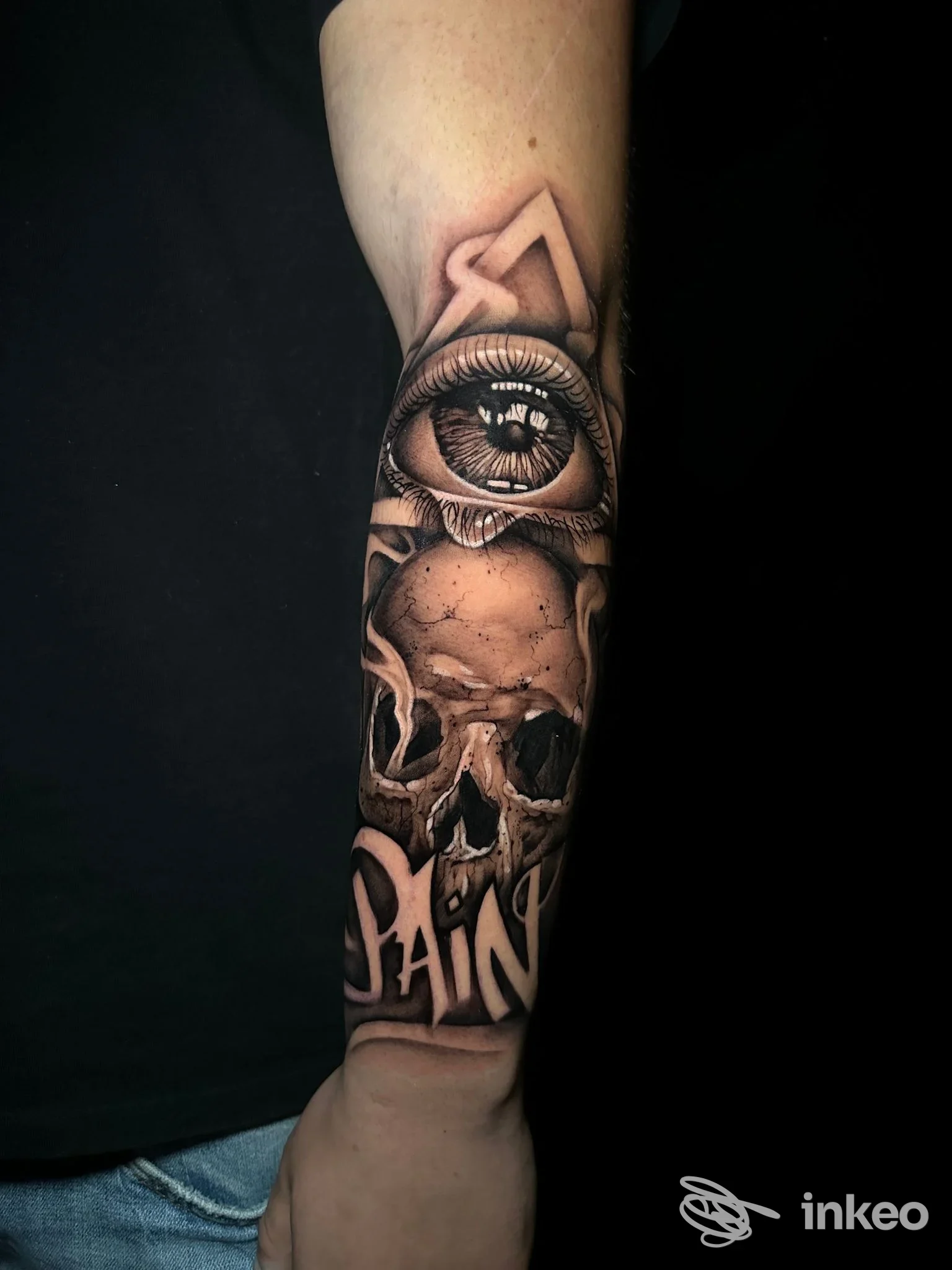 Tatuaggio realistico su avambraccio raffigurante un occhio in alto e un teschio sottostante, realizzato in bianco e nero con riflessi e sfumature intense.