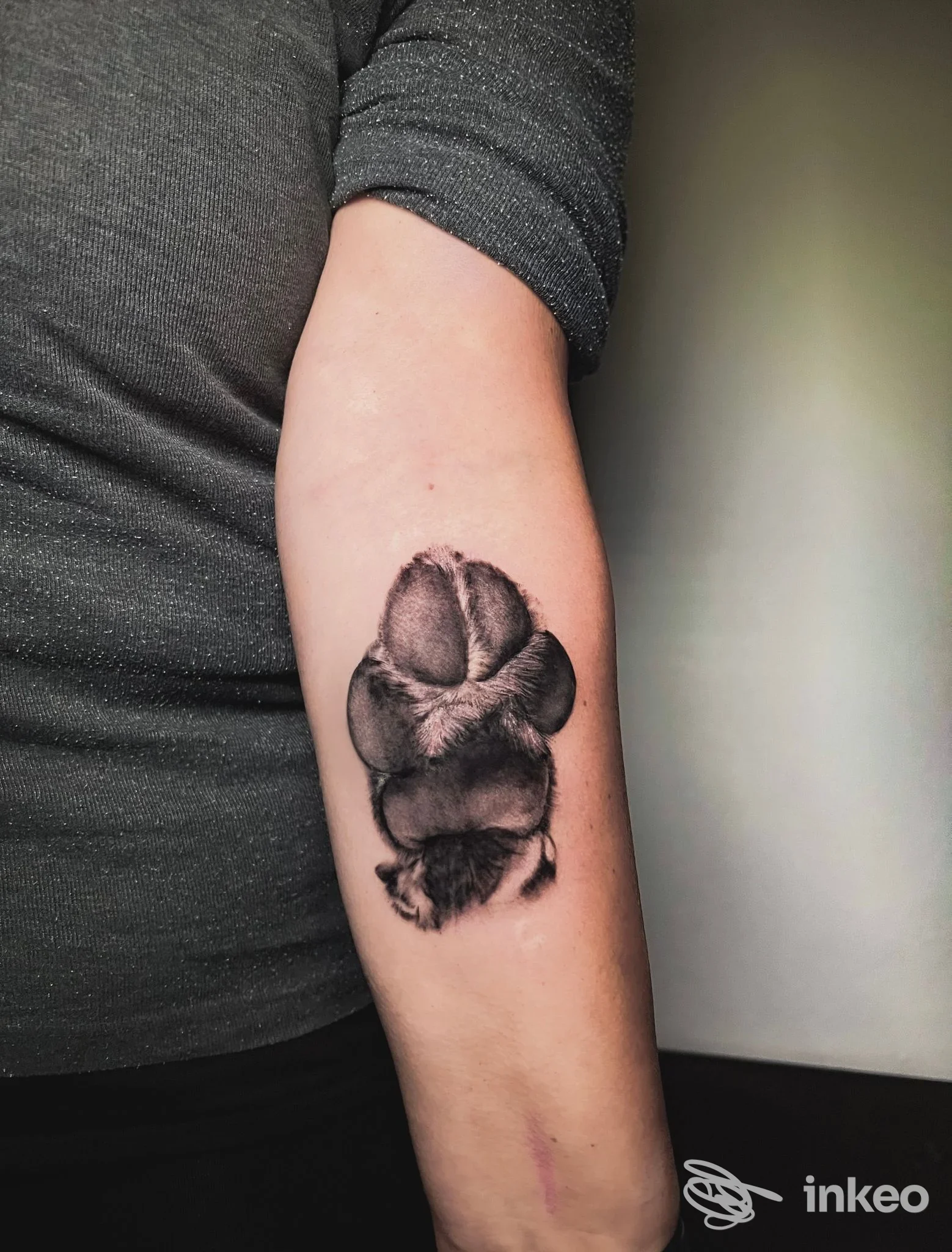 Tattoo in bianco e nero su avambraccio, raffigurante una forma vegetale o fiore stilizzato, realizzato sulla pelle di una persona, senza elementi di interfaccia o testo esterno visibile.
